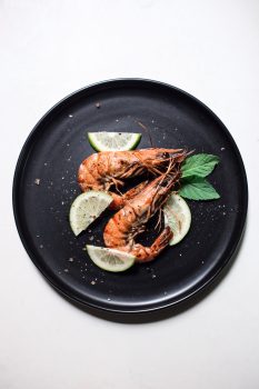 cooked shrimp on a black plate with garnishes