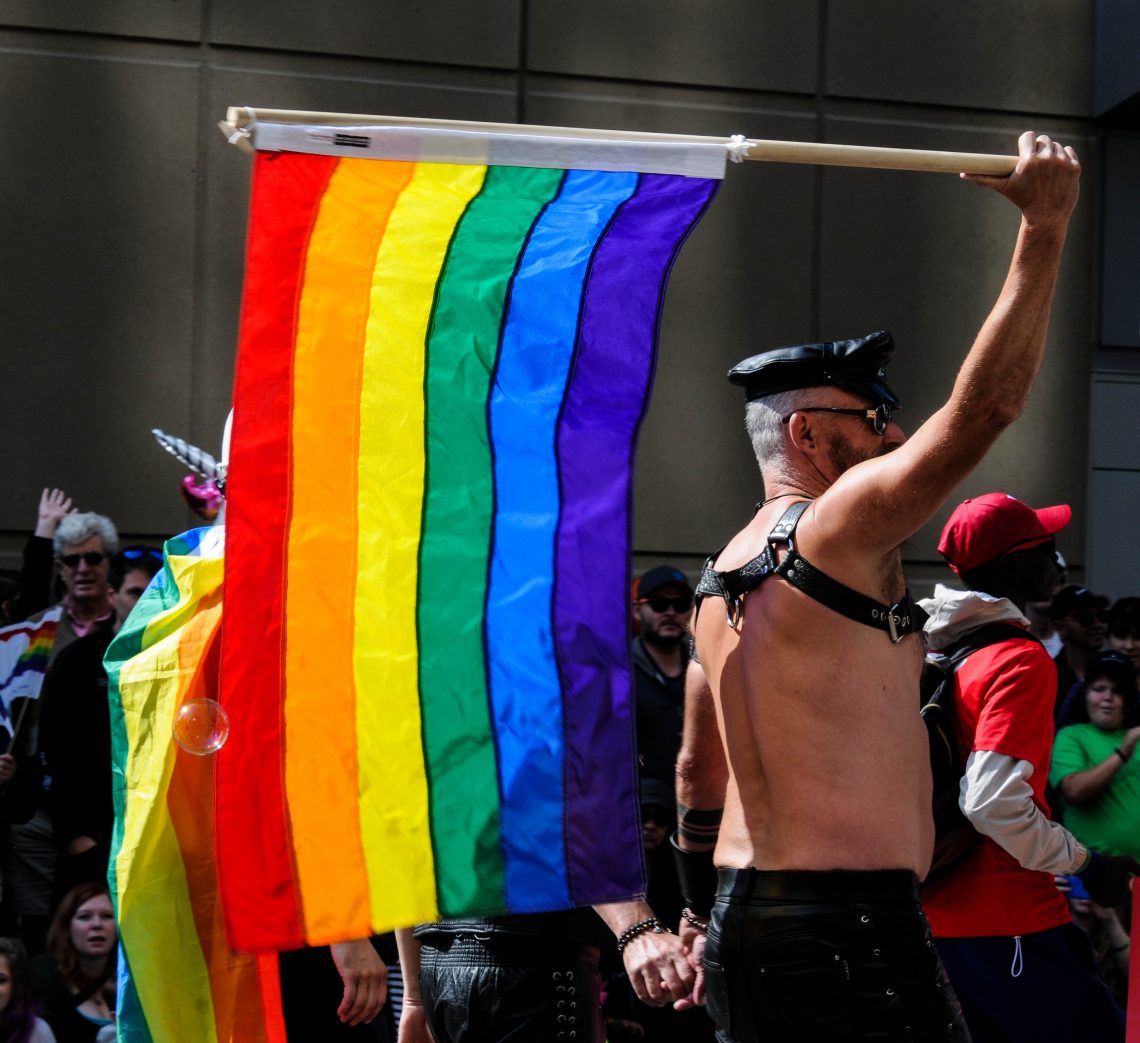 man waving flag in pride parade