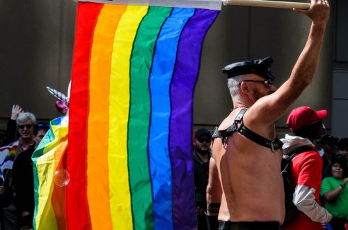 man waving flag in pride parade