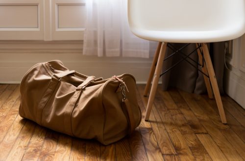 brown duffel bag beside white and brown wooden chair