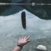 black feather falling on person's hand