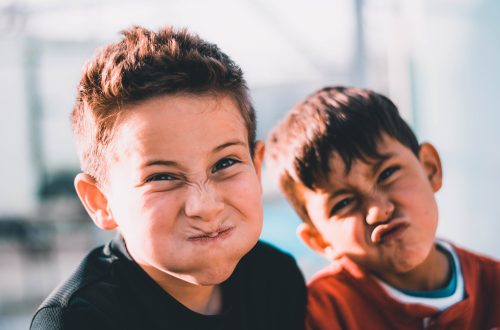 shallow focus photography of two boys doing wacky faces