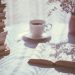 open book beside white ceramic teacup on saucer