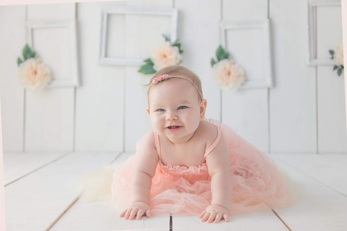 girl crawling on white floor while smiling