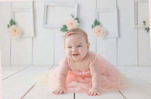 girl crawling on white floor while smiling