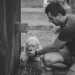 man kneeling beside girl feeding dog in grayscale photograpy