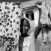 grayscale photo of boy in hat holding clothes hanger rope with clothes