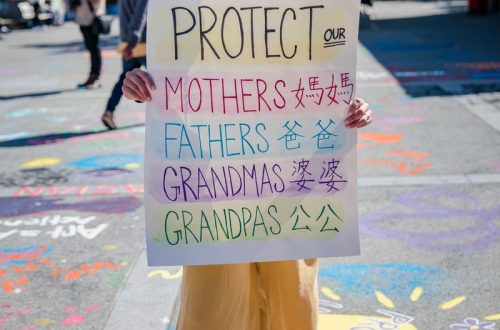 woman in yellow pants holding white an anti-violence placard