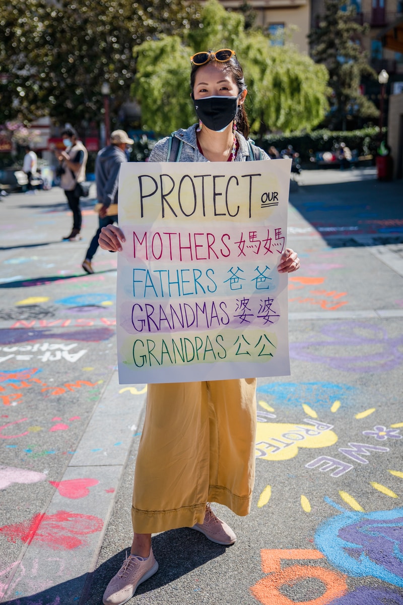 woman in yellow pants holding white an anti-violence placard